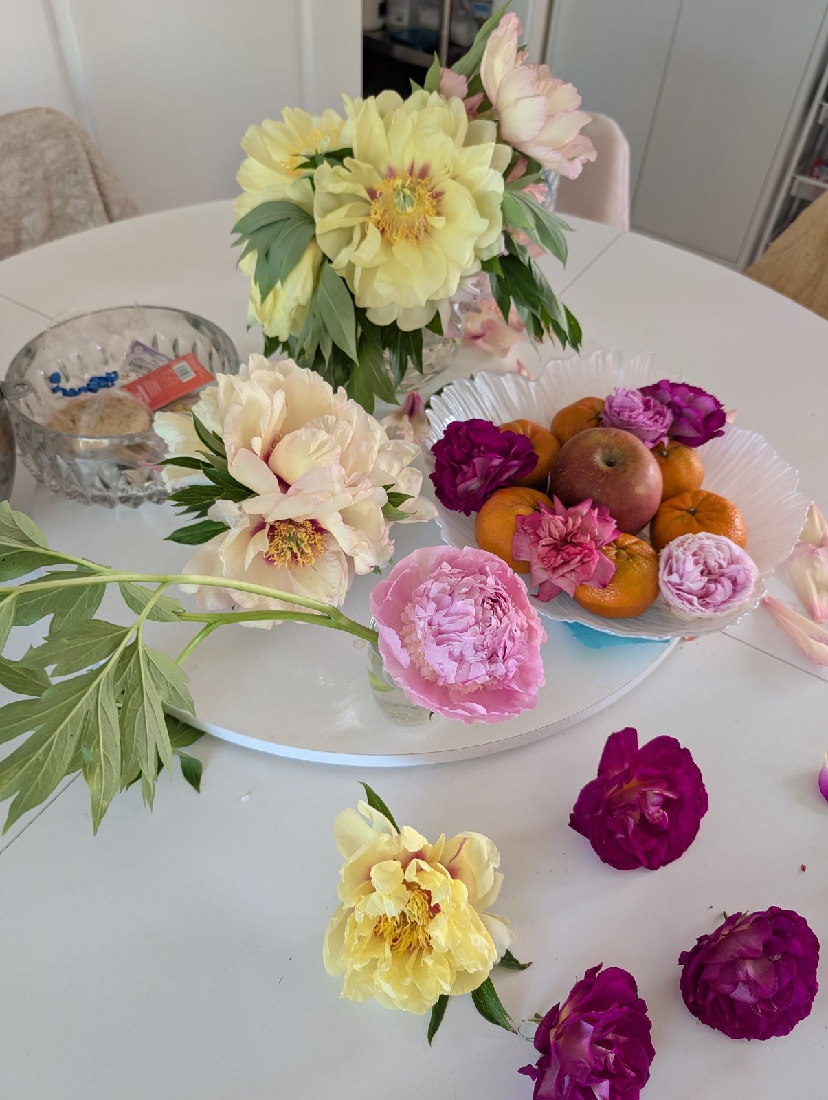 Bartzella Itoh peonies in a vase with Cora Louise, Sarah Bernhardt and magenta roses on a white table