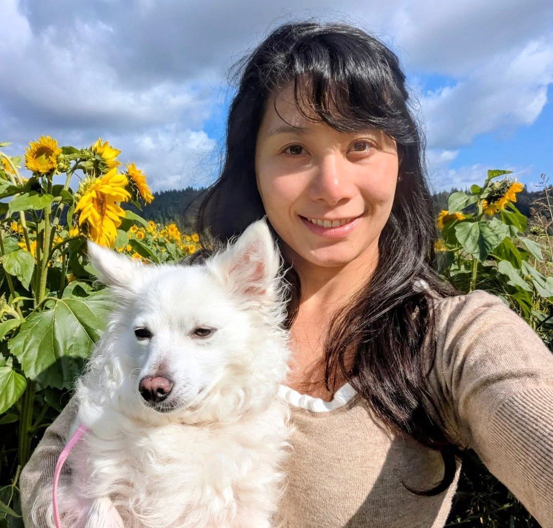 PhyTu's founder holding her white dog in a sunflower field