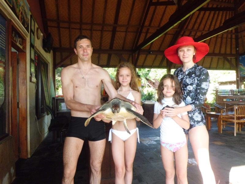 Family holding rescued sea turtle at Reef Seen Proyek Penyu hatchery Bali